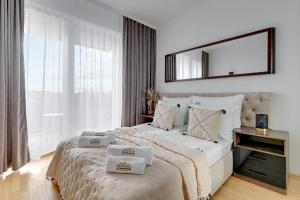 Nad Stawem by Downtown Apartments في غدانسك: غرفة نوم بيضاء مع سرير كبير مع مرآة