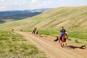 a group of people riding horses down a dirt road at Stepperiders in Ulaanbaatar