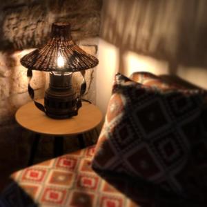 a lamp on a table next to a bed with a pillow at M&M STONE-Village House-Family-Vintage in Lindos