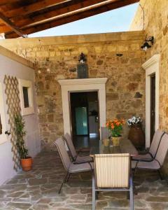 a patio with a table and chairs and a stone wall at M&M STONE-Village House-Family-Vintage in Líndos