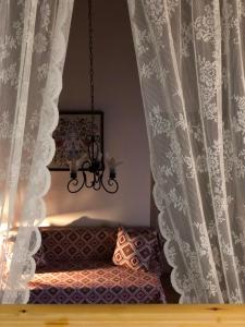 a couch in a room with curtains and a chandelier at M&M STONE-Village House-Family-Vintage in Líndos