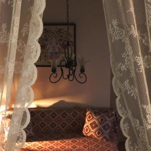 a room with a bed with curtains and a chandelier at M&M STONE-Village House-Family-Vintage in Líndos