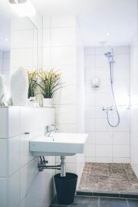 a white bathroom with a sink and a shower at Gartenstadt Hotel in Ludwigshafen am Rhein