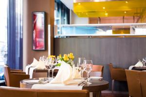 un comedor con mesas y sillas y copas de vino en Novotel Aachen City, en Aachen