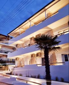 um edifício com uma palmeira em frente em Mystery Suites and Apartments em Neoi Poroi