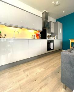 an open kitchen with white cabinets and a blue wall at City Views from modern apartment in Bristol