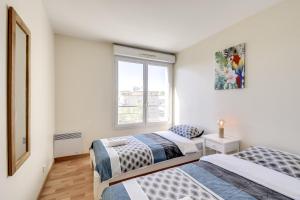 two beds in a room with a window at Chic apart avec terrace et parking in Cergy