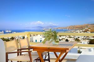 un tavolo in legno con sedie e un balcone con vista. di Pelican Hotel a Mykonos Città