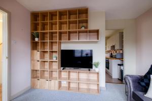 a living room with a flat screen tv and wooden shelves at Banchory House - SJA Stays - 2 Bed Apartment in Banchory