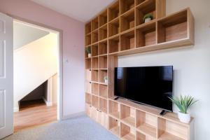 a living room with a tv and a wall of shelves at Banchory House - SJA Stays - 2 Bed Apartment in Banchory