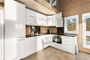 uma cozinha com armários brancos e uma parede de madeira em Moderne hytte met eindeloos uitzicht en een sauna em Vradal