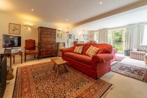 uma sala de estar com um sofá vermelho e uma televisão em Saxon Shore Cottage em Burnham Deepdale