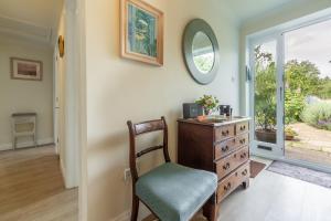 um quarto com uma cómoda, uma cadeira e um espelho em Saxon Shore Cottage em Burnham Deepdale