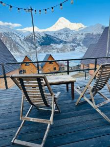 two chairs and a picnic table on a deck with mountains at Guesthouse Elli & Cottages in Kazbegi