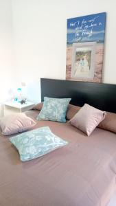 Una cama con almohadas rosas y azules. en Appartamenti Cala del Sole - INFINITYHOLIDAYS en Costa Paradiso