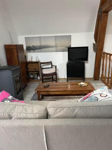 a living room with a couch and a flat screen tv at Duplex à la campagne in Vermenton +2 photos