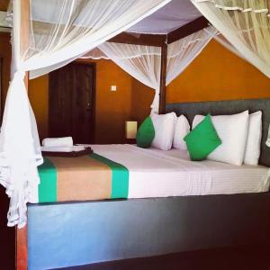a bedroom with a bed with green and white pillows at Cabanas by Cloudz Sigiriya in Sigiriya