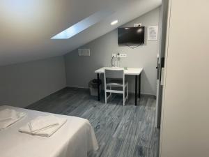 Zimmer mit einem Bett, einem Schreibtisch und einem TV in der Unterkunft casa julian-inn in Madrid