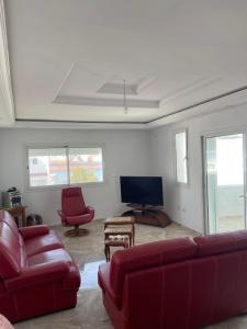 a living room with red furniture and a flat screen tv at Appartement de luxe, Résidence les 5 étoiles, Bizerte in Zarzouna