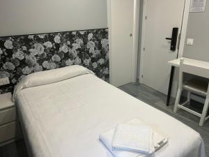 Cama blanca en habitación con papel pintado con motivos florales en casa julian-inn, en Madrid