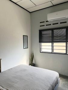 a white bedroom with a bed and a window at Mulan Guest House with Forest Bathtub in Pantai Cenang