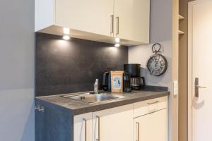 uma cozinha com um lavatório e um relógio na parede em Logierhaus K15 Appartement 6 em Borkum
