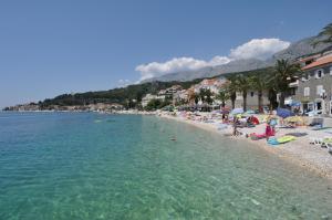 a beach with a bunch of people sitting in the water at Villa BORIĆ DARKO in Podgora