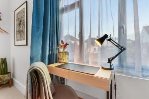 een bureau met een lamp voor een raam bij Modern Double bedroom in city apartment room 1 in Londen