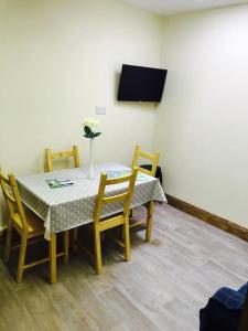 a table with chairs and a vase with flowers on it at Barber’s hall town center apartment in Belmullet