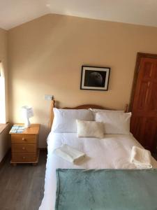 a bed with white sheets and pillows in a bedroom at Barber’s hall town center apartment in Belmullet