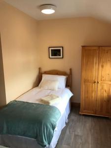 a bedroom with a bed and a wooden cabinet at Barber’s hall town center apartment in Belmullet