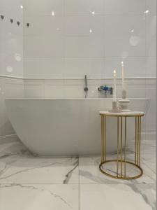 een badkamer met een bad en een tafel met twee kaarsen bij Wilson Apartamenty in Poznań