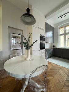 een witte keuken met een witte tafel en stoelen bij Wilson Apartamenty in Poznań