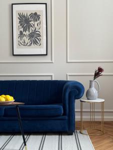 um sofá azul numa sala de estar com uma mesa em Wilson Apartamenty em Poznań