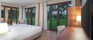 Nirvana Mediterranean Excellence - Ultra All Inclusive في بيلديبي: غرفة نوم بسرير ومكتب ونوافذ