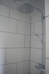 een douche met een douchekop in de badkamer bij Vakantiehuisje Te Gast op Texel in Den Burg