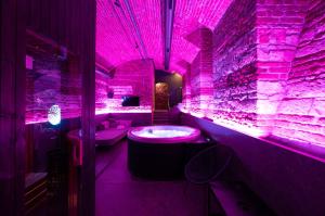 a purple bathroom with a tub and a stone wall at SPA SPA Opletalova in Prague