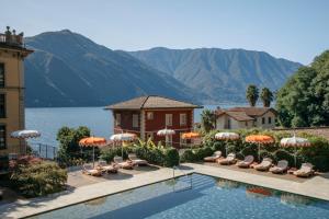 a resort with a swimming pool with chairs and umbrellas at Grand Hotel Tremezzo in Tremezzo