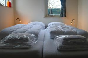 een groep kussens op een bed in een kamer bij Vakantiehuisje Te Gast op Texel in Den Burg