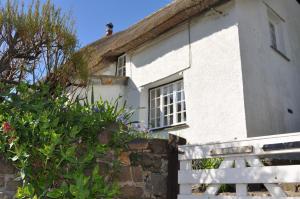una casa blanca con una valla delante en Old Cottage, Crackington Haven, North Cornwall, en Bude