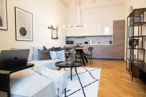 een woonkamer met een bank en een tafel met een laptop bij Cozy Industrial 8min Dancing House APT in Praag