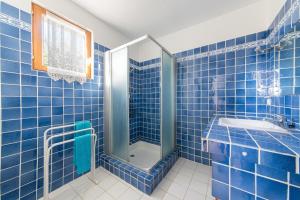 La salle de bains est pourvue de carrelage bleu, d'une douche et d'un lavabo. dans l'établissement Les Olivettes - Maison très calme Parking privé, à Régusse 6 autres photos