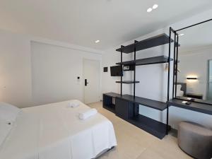 a bedroom with a white bed and a black shelf at Adele Hotel Ksamil in Ksamil