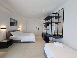 a bedroom with two beds and a black shelf at Adele Hotel Ksamil in Ksamil