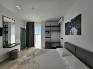 a bedroom with a large white bed and a mirror at Adele Hotel Ksamil in Ksamil