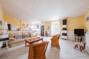 a living room with a couch and a table and chairs at La petite Grange - Parking privé - A 2km de la mer in Saint-Georges-dʼOléron