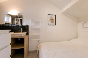 a white bedroom with a sink and a bed at 2km des plages- Bassin d'Arcachon- Cocon pour 2 in Lanton