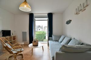 ein Wohnzimmer mit einem Sofa und einem Stuhl in der Unterkunft Bruyères - Appartement vue mer à 150m de la plage in Saint-Cast-le-Guildo