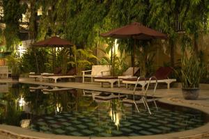 a pool with chairs and umbrellas in a building at Monoreach Angkor Hotel in Siem Reap