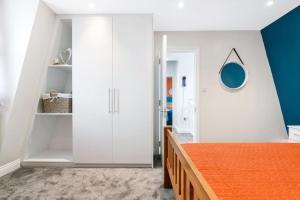 a bedroom with white cabinets and an orange bed at Stunning Double Rooms within a Loft space in London +3 photos